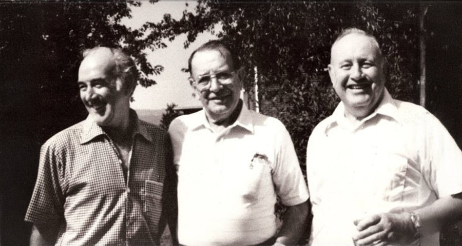 An old black and white photo of three men smiling outdoors